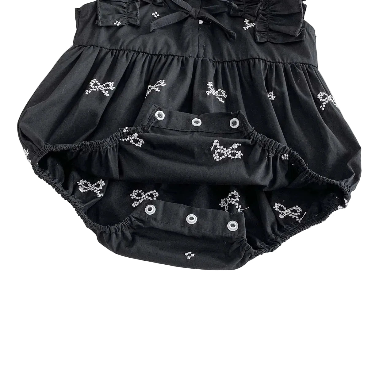 Close up of the bottom crotch area of a black baby romper showing open snap closures for easy diaper changes.