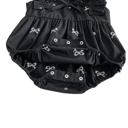 Close up of the bottom crotch area of a black baby romper showing open snap closures for easy diaper changes.