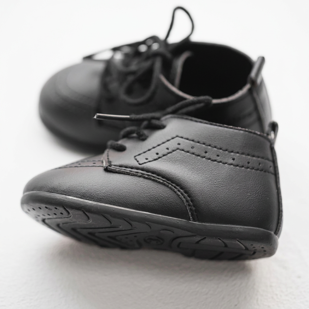 Side and bottom view of Kidsely black baby dress shoes highlighting the flexible non-slip rubber outsole traction pattern for early walkers.