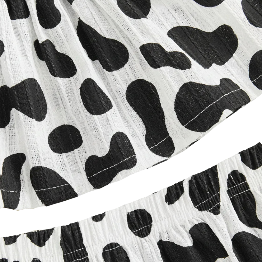 Close-up showing the elastic waistband of the black and white cow print shorts and the bottom hem of the matching top.
