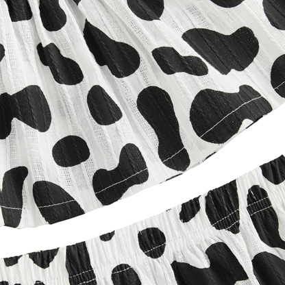 Close-up showing the elastic waistband of the black and white cow print shorts and the bottom hem of the matching top.