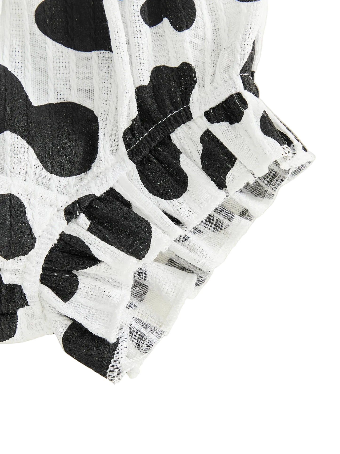 Close-up of the ruffled hem on the black and white cow print baby shorts.
