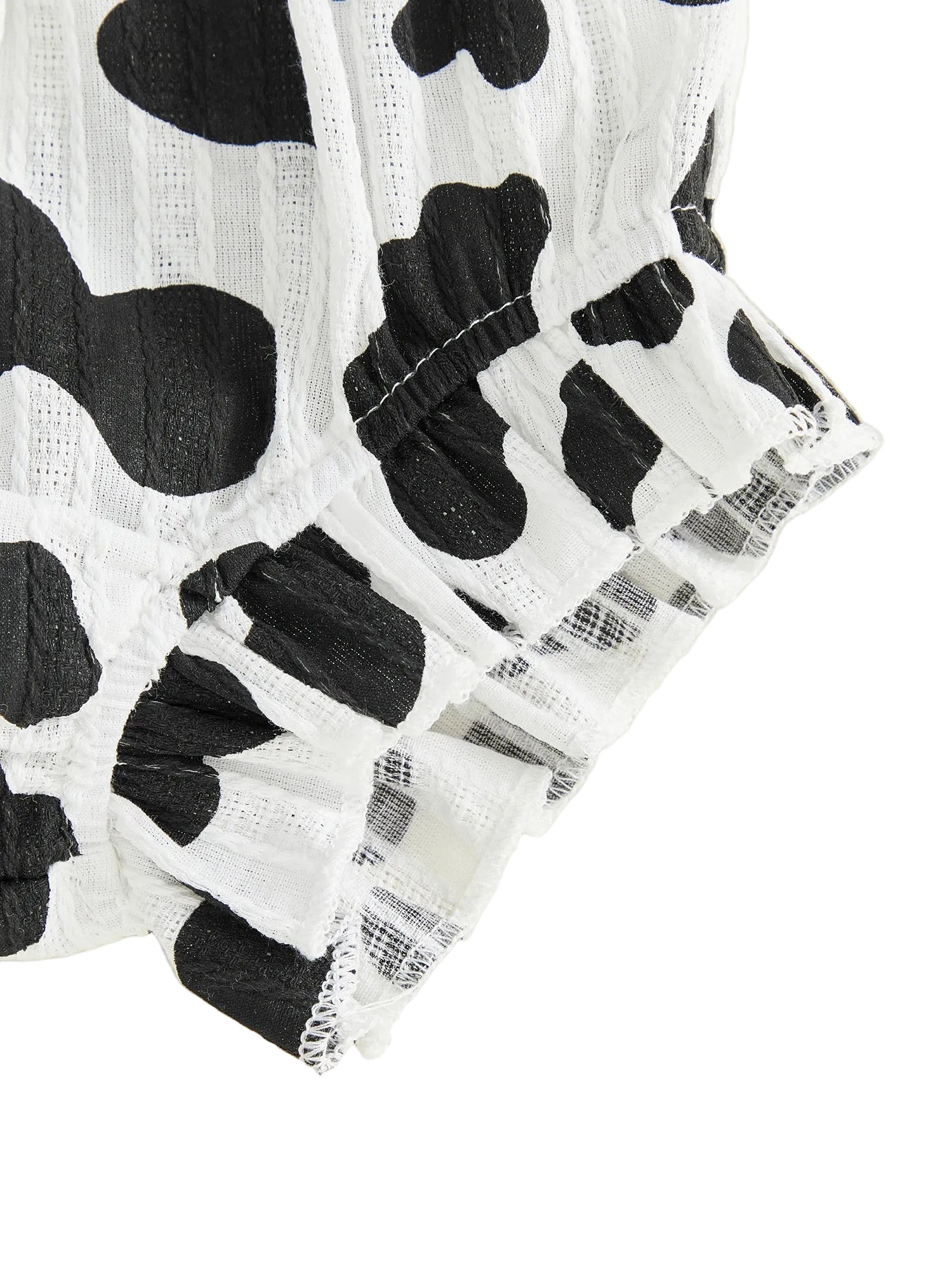 Close-up of the ruffled hem on the black and white cow print baby shorts.