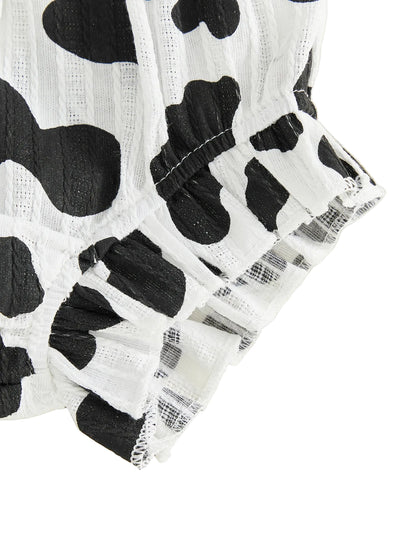 Close-up of the ruffled hem on the black and white cow print baby shorts.
