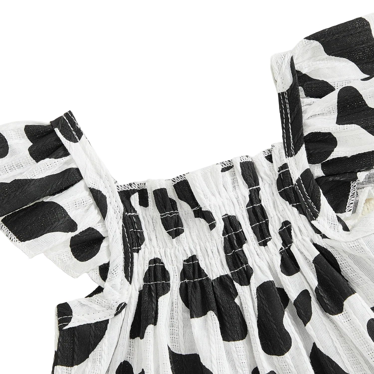 Close-up detail of the black and white cow print smocked top with ruffled flying sleeves.
