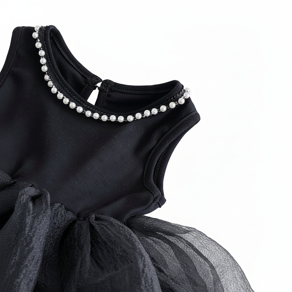 An angled close-up view of the black dress bodice, showing the armhole and the pearl neckline.