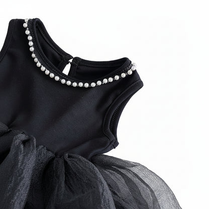 An angled close-up view of the black dress bodice, showing the armhole and the pearl neckline.