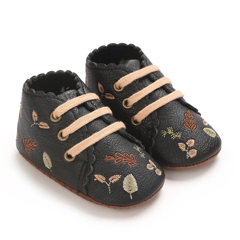 Pair of black boho embroidered baby girl booties with scalloped edges.