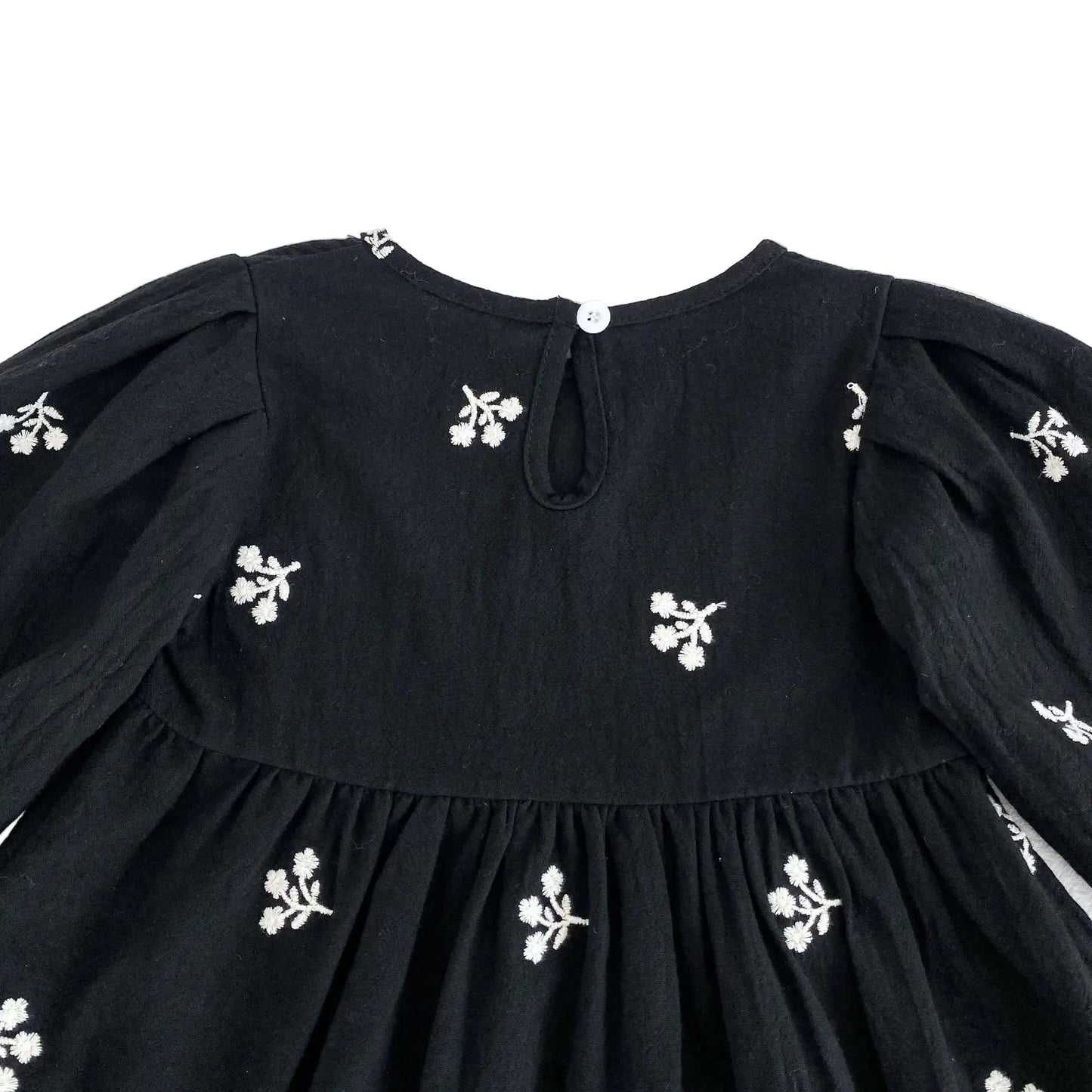 Close-up of the back keyhole button closure on the toddler girls black floral dress.