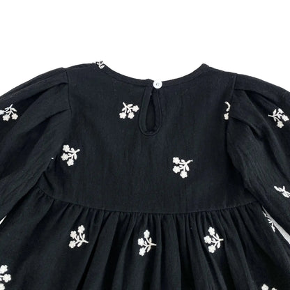Close-up of the back keyhole button closure on the toddler girls black floral dress.