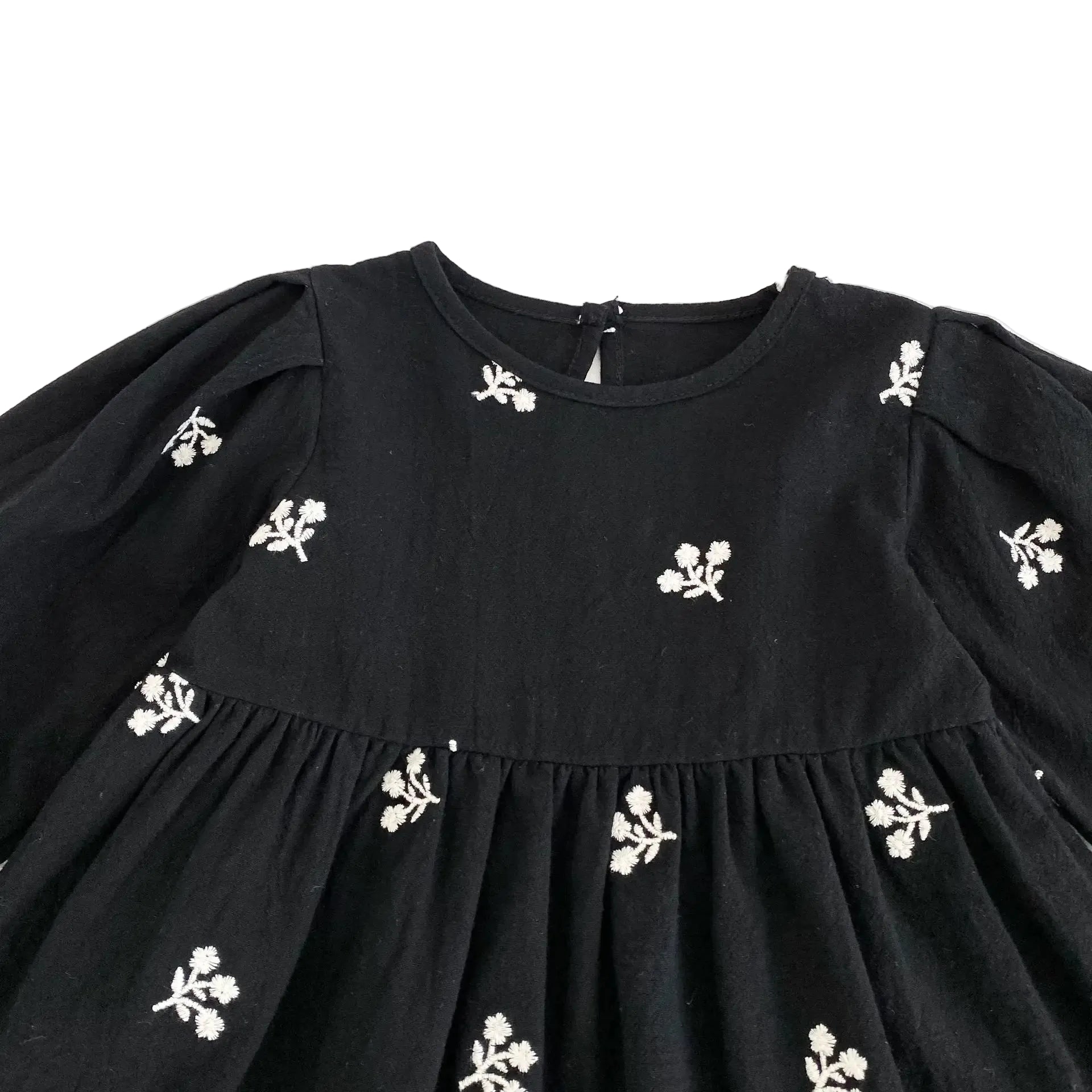 Close-up of the round neckline and white floral embroidery on the front bodice of the black toddler dress.