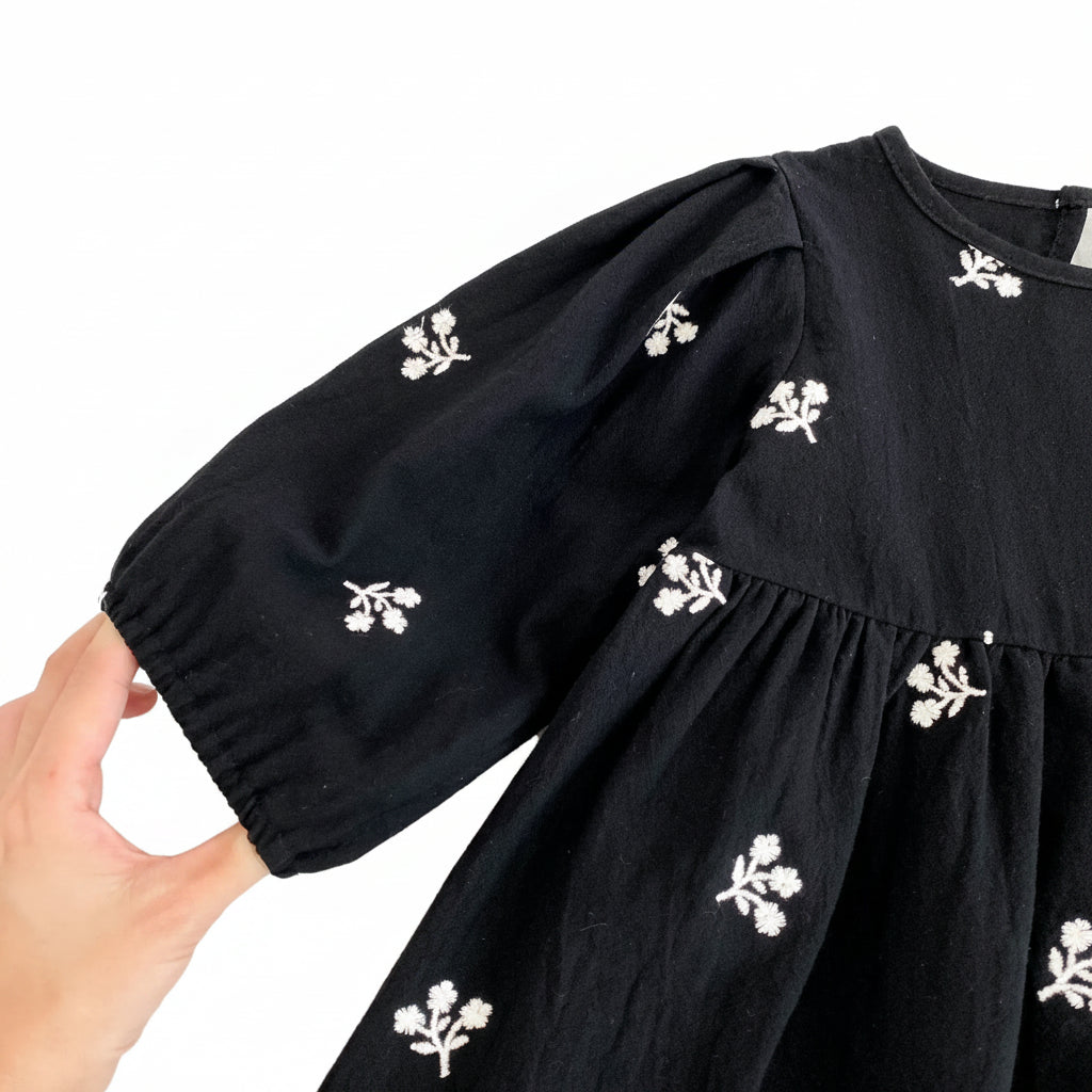 Close-up showing the gathered elastic cuff on the puff sleeve of the toddler girls black dress.