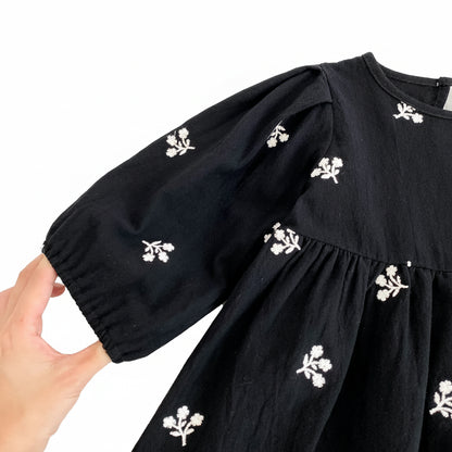 Close-up showing the gathered elastic cuff on the puff sleeve of the toddler girls black dress.