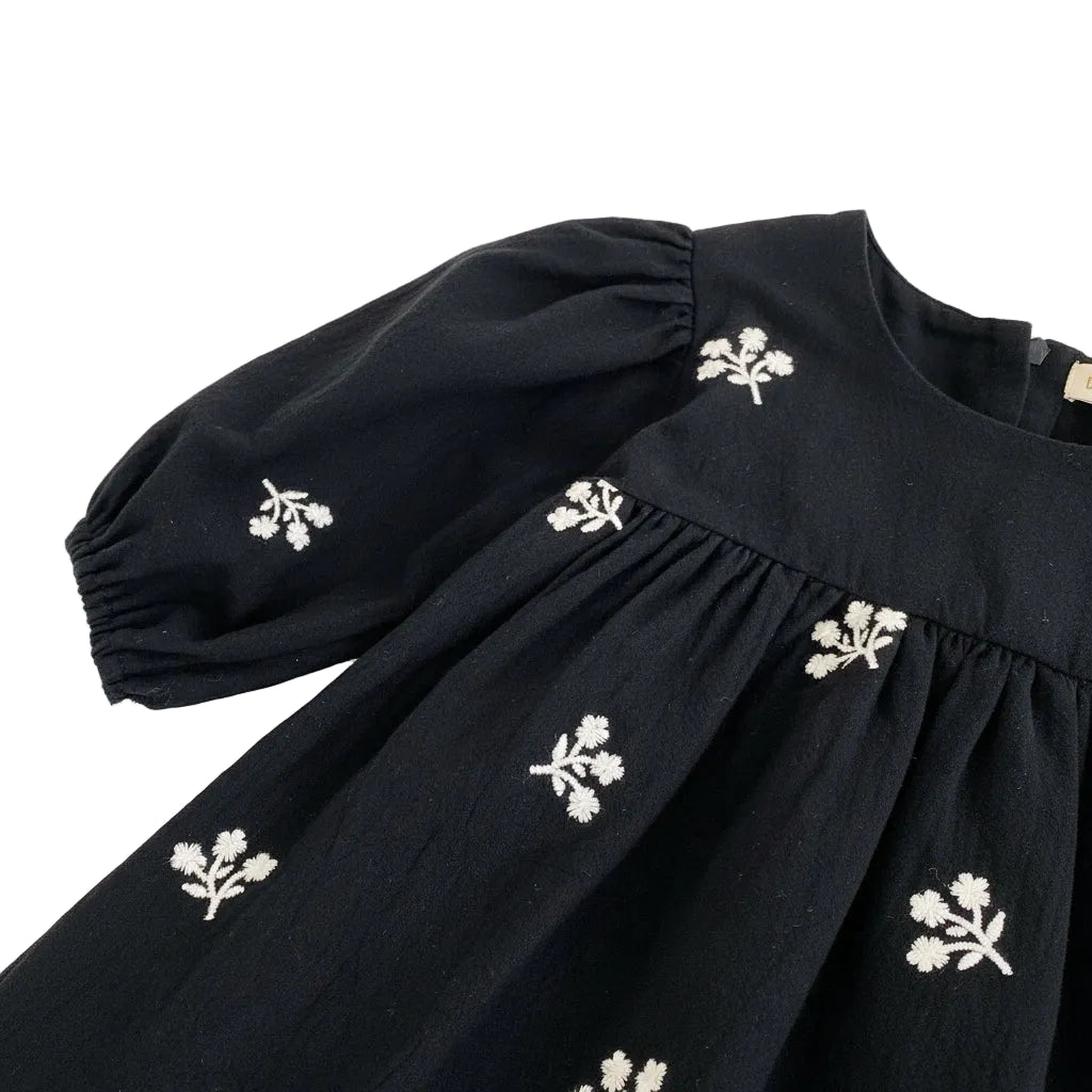 Close-up of the shoulder seam and draped puff sleeve on the black floral embroidered toddler dress.