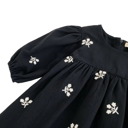 Close-up of the shoulder seam and draped puff sleeve on the black floral embroidered toddler dress.