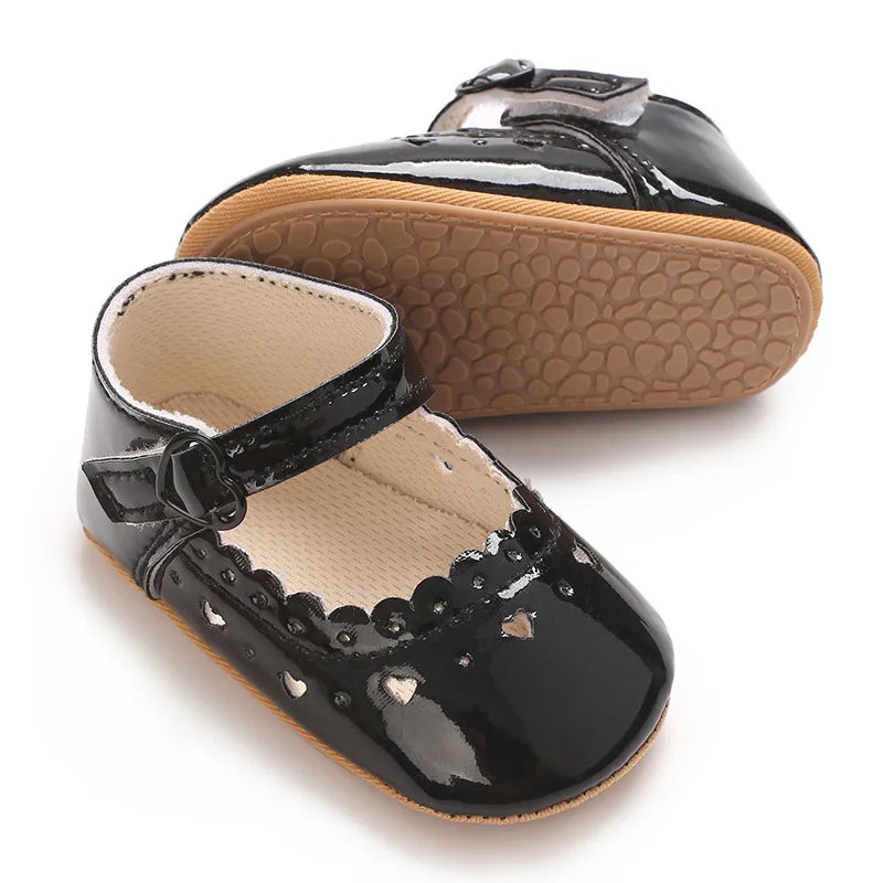 Pair of black baby girl Mary Jane shoes showing the flexible soft sole.
