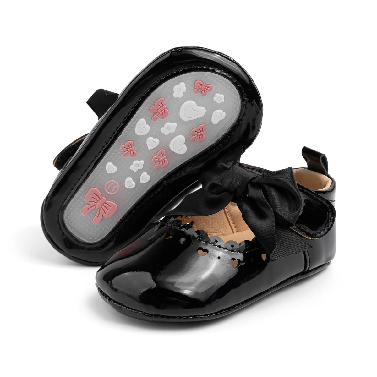 Bottom of a black baby shoe showing the flexible PVC anti-slip sole with butterfly and cloud grip patterns.