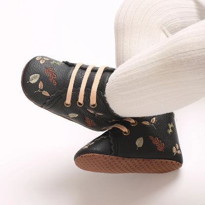Baby wearing black embroidered soft sole pre-walker booties.
