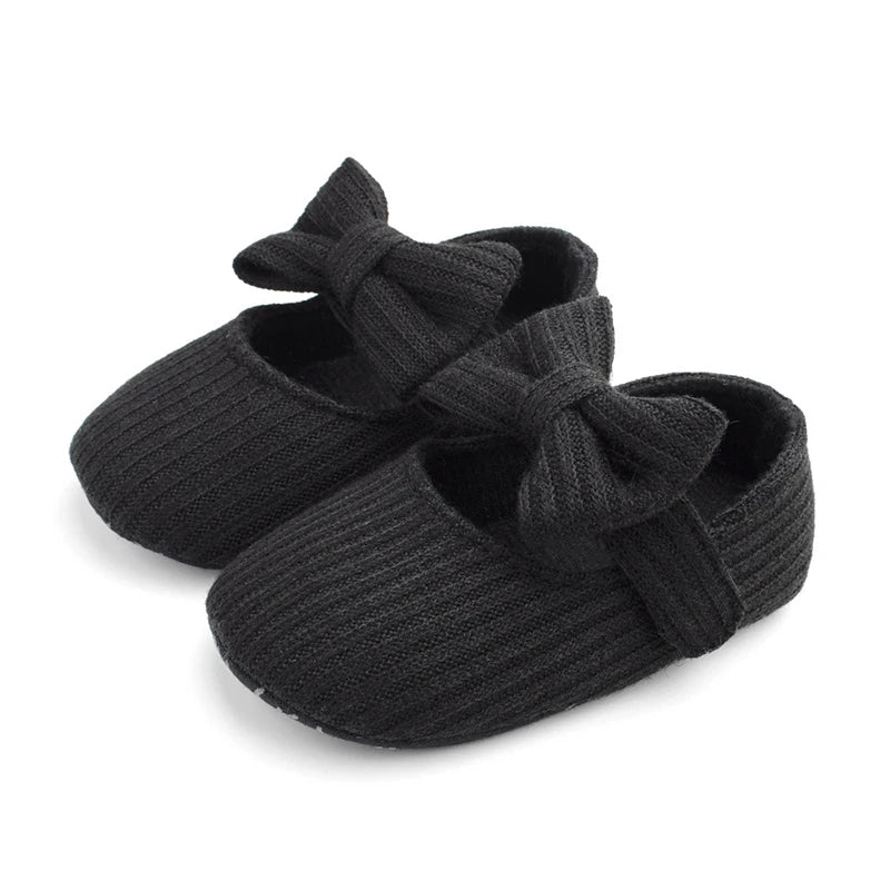 Pair of black ribbed knit Mary Jane crib shoes with front bows.