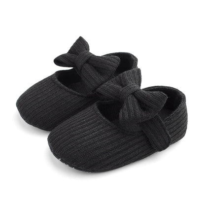 Pair of black ribbed knit Mary Jane crib shoes with front bows.
