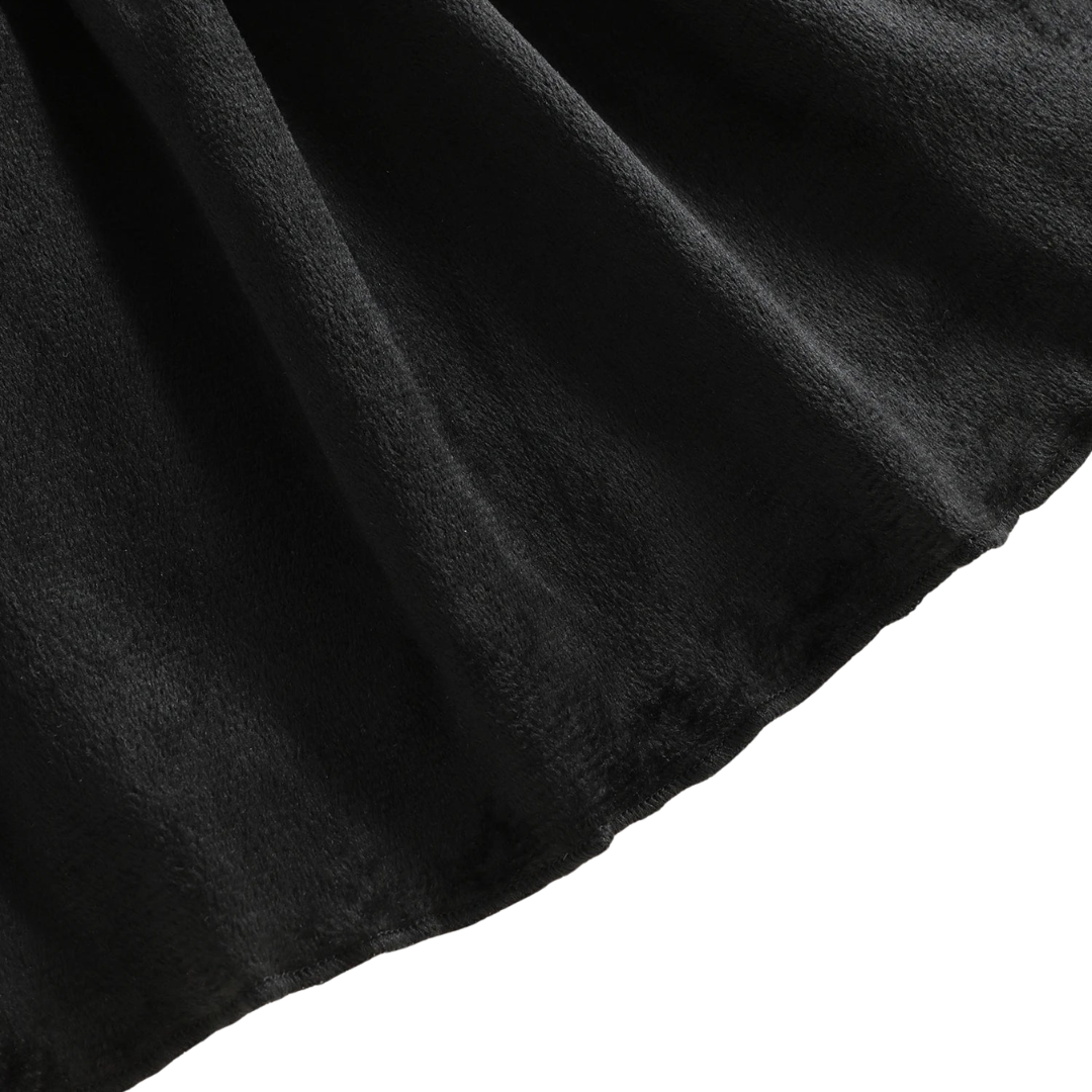 Close-up showing the soft, textured black fabric and draped hem of the girls Halloween dress.