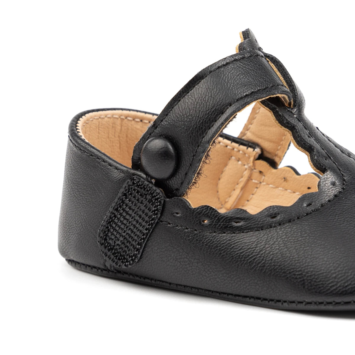 Close-up of the black baby girl T-strap shoe showing the hook-and-loop velcro closure and faux button detail.