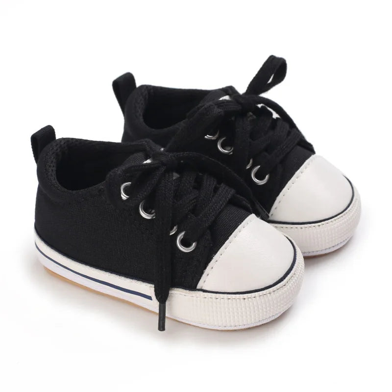 Versatile black unisex baby sneakers with white contrast stitching and rubber outsole.