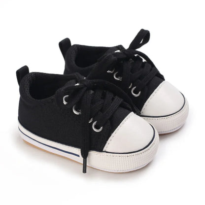 Versatile black unisex baby sneakers with white contrast stitching and rubber outsole.