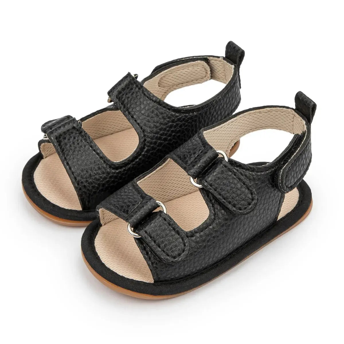 Infant black vegan leather sandals showing the textured anti-slip outsole and secure hook-and-loop closure.