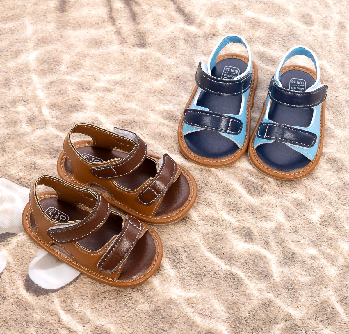 Blue and brown baby boy summer sandals sitting together on the sand.