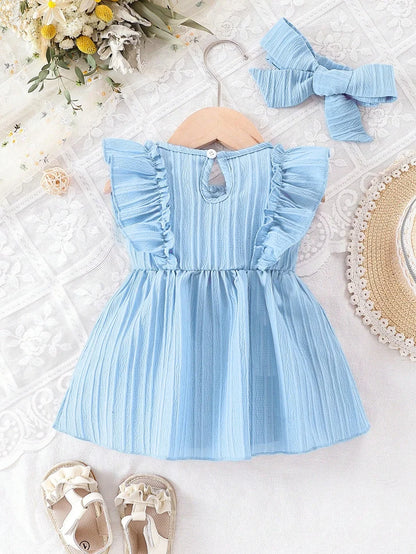 Back view of the light blue baby summer dress on a wooden hanger, showing the easy back-button closure design.