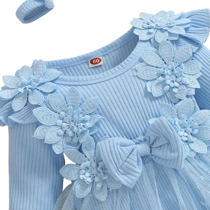 Close up of the blue baby girl romper dress highlighting the ribbed texture, 3D floral appliques, and statement bow.