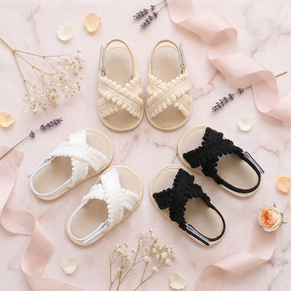 Group flat lay of beige, white, and black boho baby sandals with floral accents.