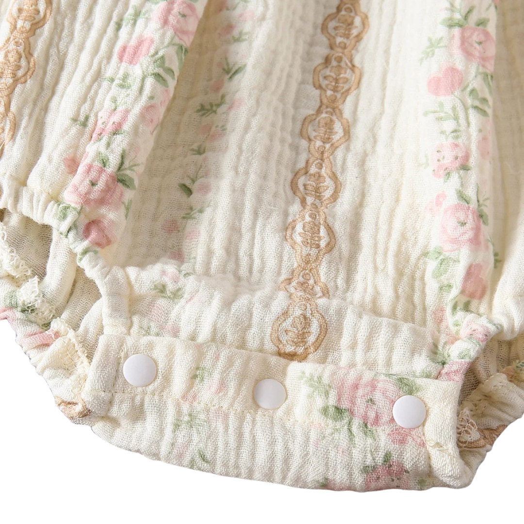 Close-up of the bottom gusset on a baby girl's bubble romper, highlighting the convenient snap closures for easy diaper changes.