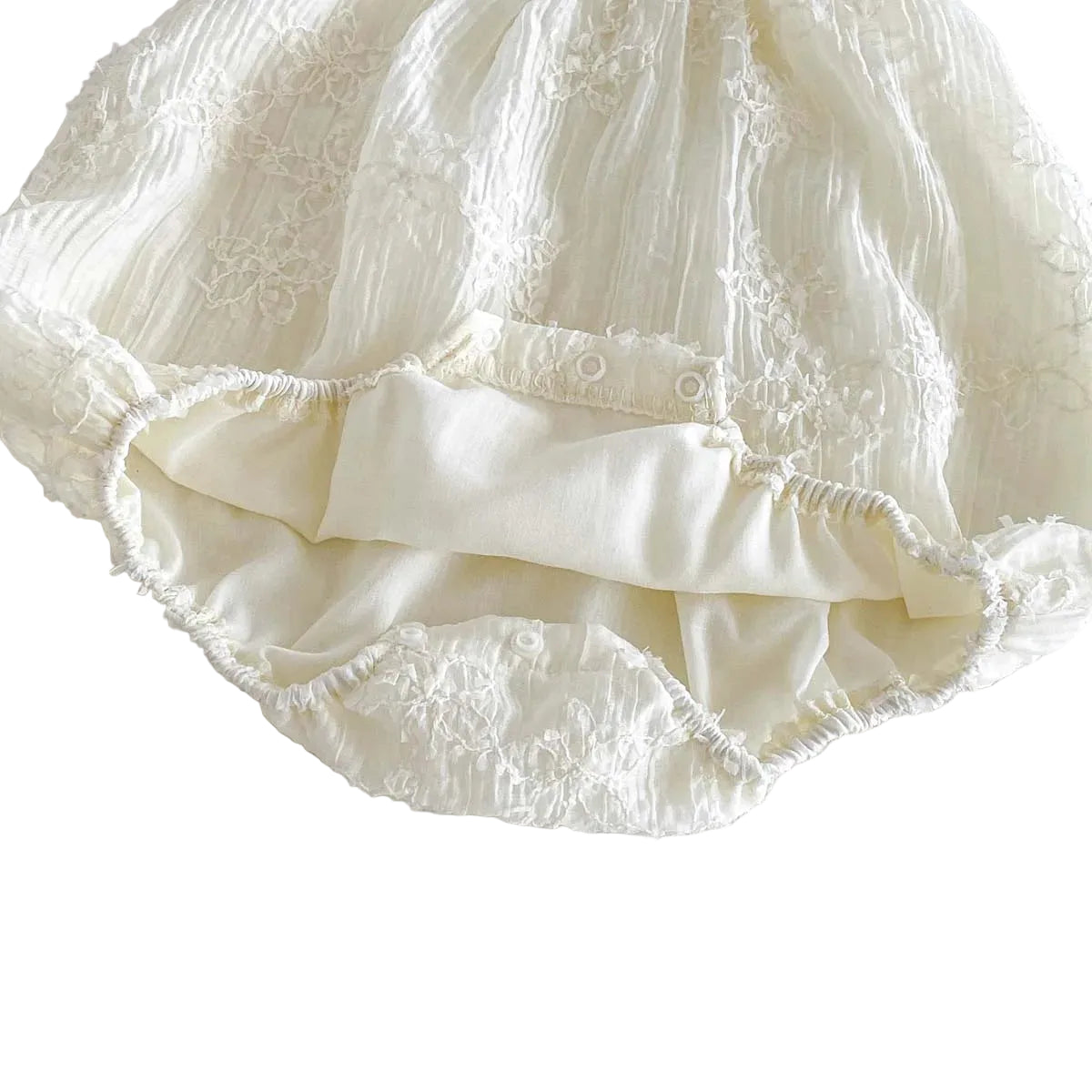 Inside view of the white baby romper showing the bottom snap closures for diaper changes and the soft inner lining.