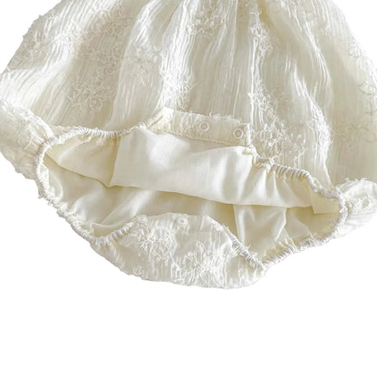 Inside view of the white baby romper showing the bottom snap closures for diaper changes and the soft inner lining.