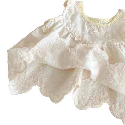 Soft and breathable layered fabric of a white floral baby tunic showing the high-quality embroidery and sheer lace finish.