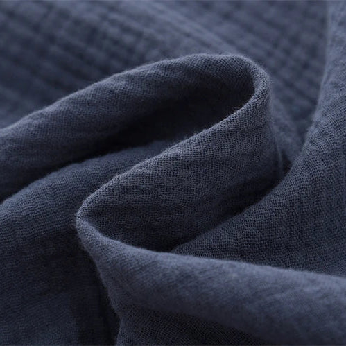 Close-up showing the soft, crinkled texture of the breathable cotton muslin fabric in navy blue.