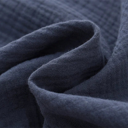 Close-up showing the soft, crinkled texture of the breathable cotton muslin fabric in navy blue.