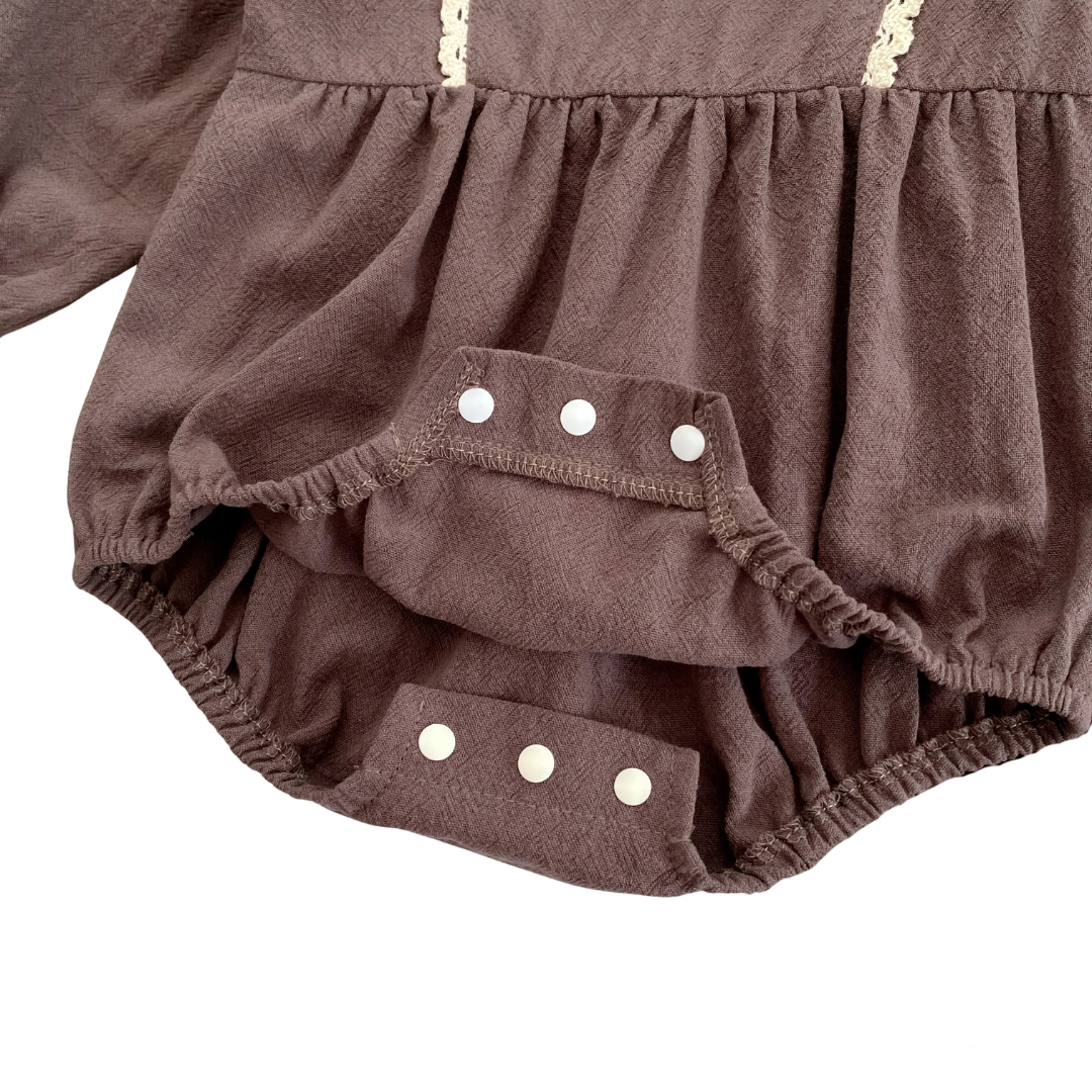 Close-up showing the unfastened bottom snap closures on the brown cotton bubble romper for easy diaper changes.