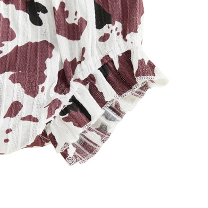 Close-up of the ruffled hem and textured fabric on the brown and white cow print baby shorts.