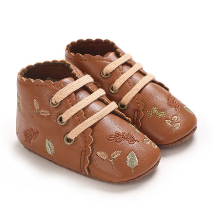 Pair of brown boho embroidered baby girl booties with scalloped edges.