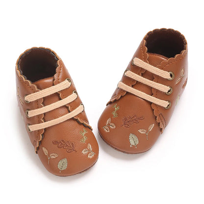 Top-down view of brown scalloped baby girl crib shoes.