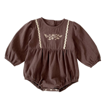 Front view of a vintage-inspired brown long sleeve baby girl bubble romper featuring floral embroidery and lace trim on the chest.