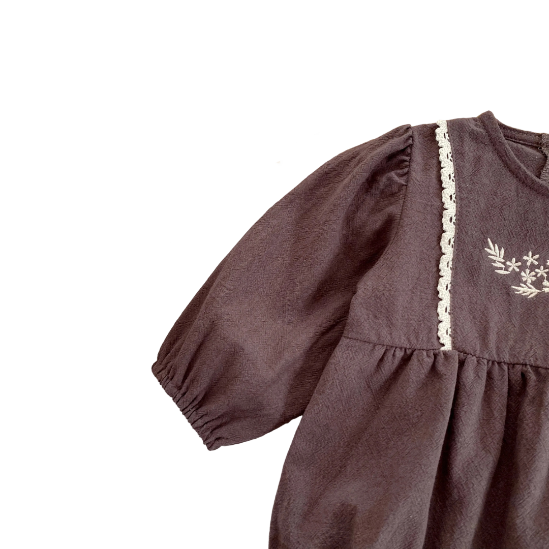 Close-up of the long sleeve and shoulder seam on the brown breathable cotton baby girl romper.