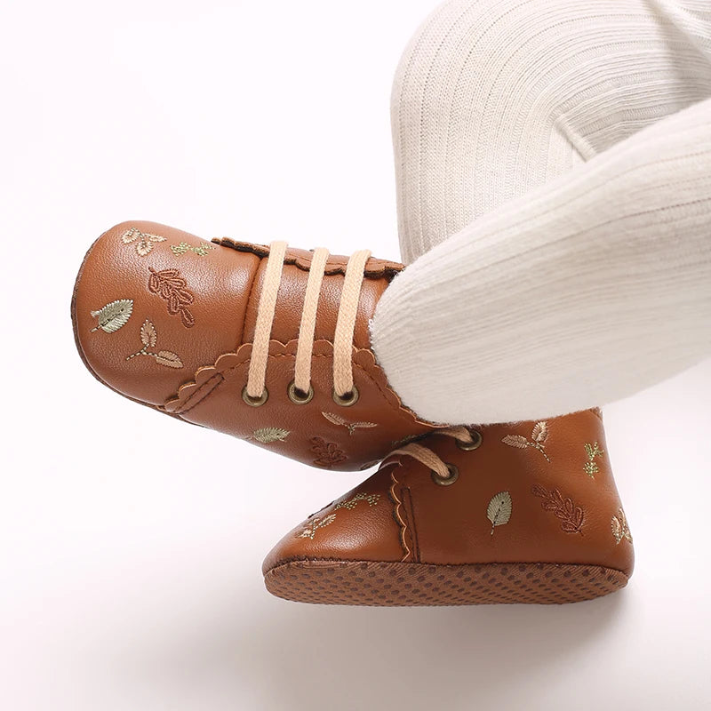 Baby wearing brown embroidered soft sole pre-walker booties.
