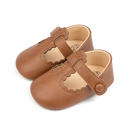 Pair of brown infant girl T-strap soft sole shoes featuring scalloped edges and a faux-button closure.