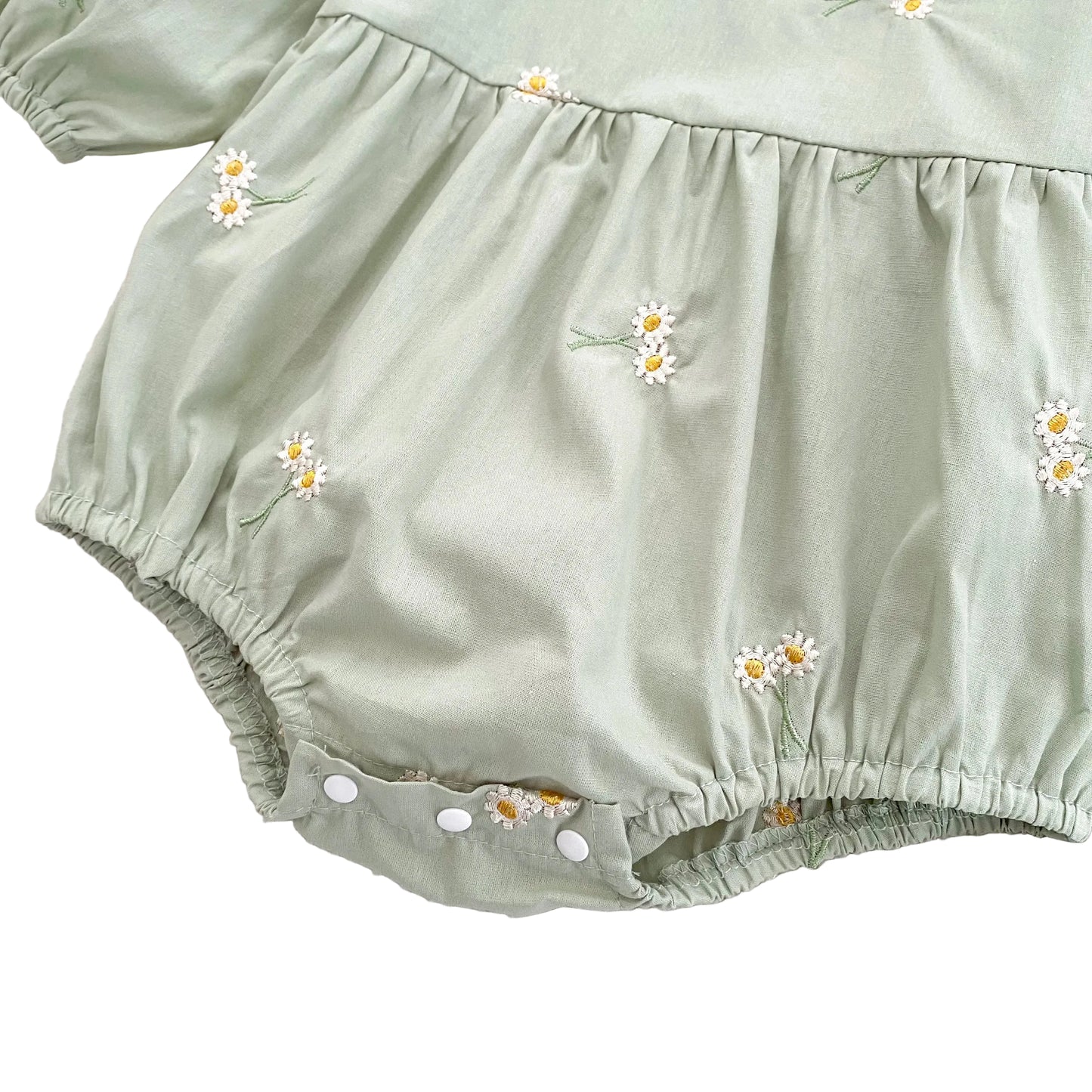 Detailed view of the gathered waistband and pleated bubble silhouette on the front of the sage green baby romper.