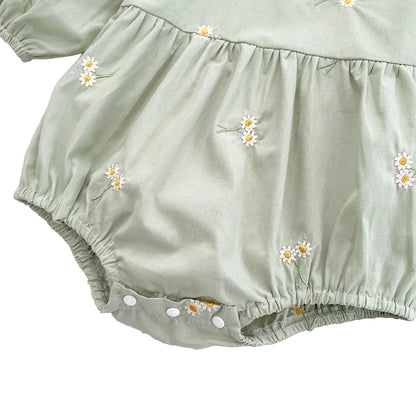 Detailed view of the gathered waistband and pleated bubble silhouette on the front of the sage green baby romper.