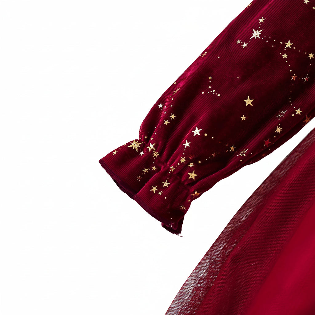 Close up of the burgundy velvet long sleeve showing the gold star pattern and delicate ruffle cuff detail.